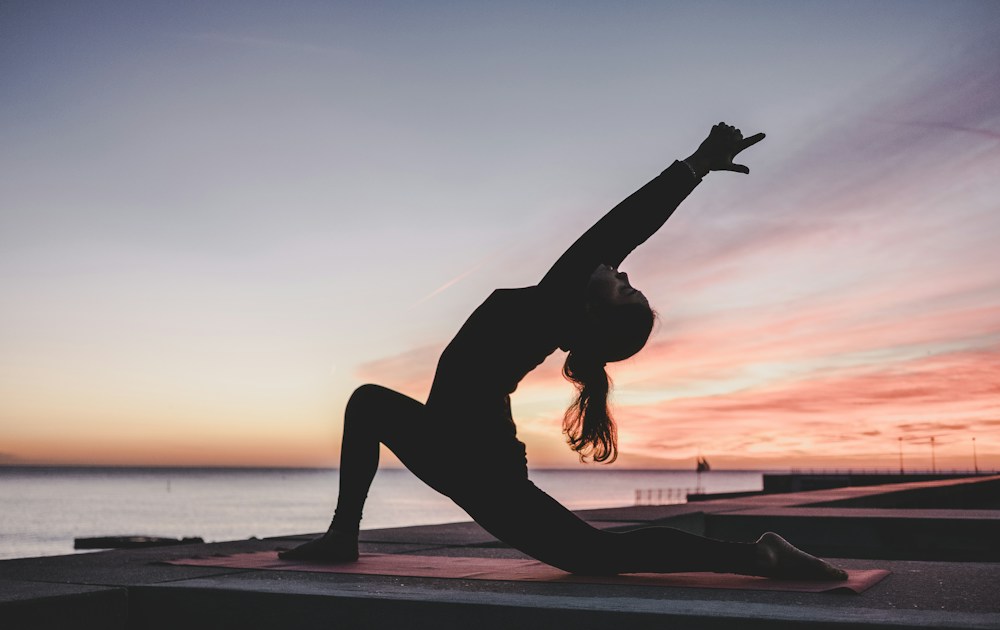 Mulher praticando alongamento ao ar livre ao pôr do sol